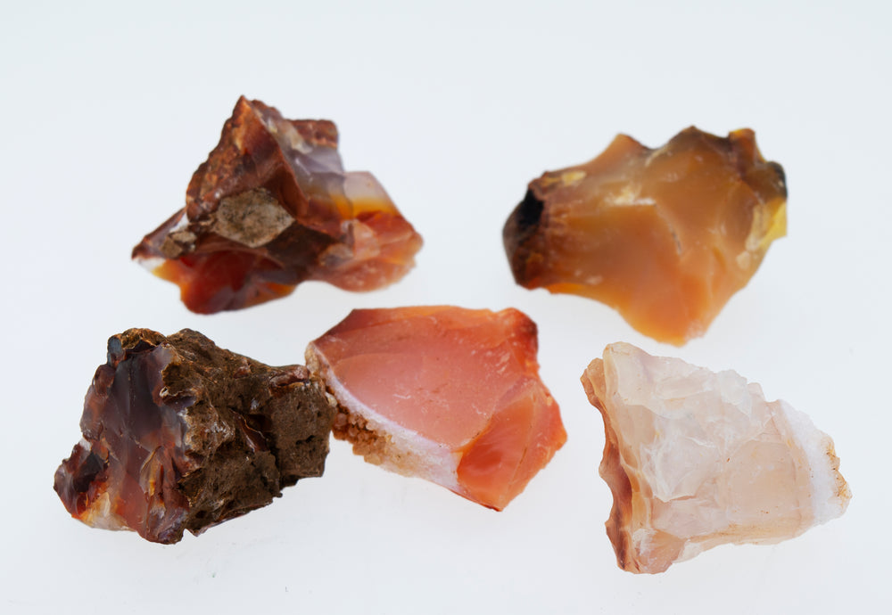 A group of Raw Carnelian Crystals arranged decoratively on a white surface.