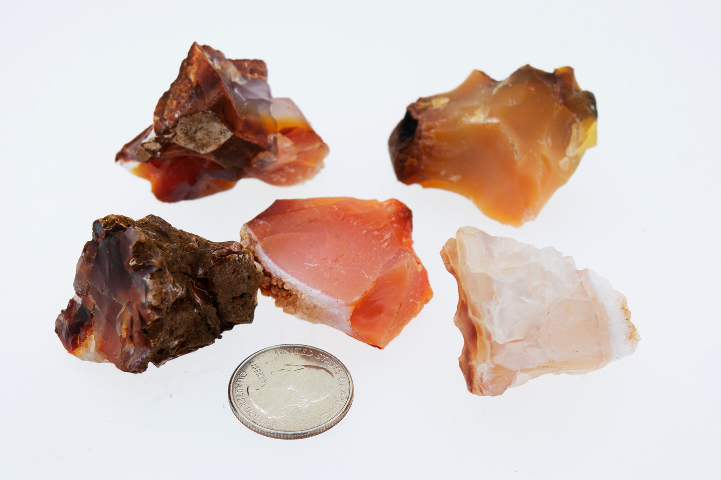 A group of Raw Carnelian Crystals next to a quarter.