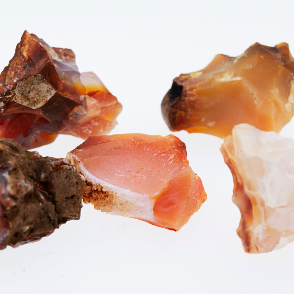 
                  
                    A cluster of raw carnelian crystals on a white background.
                  
                