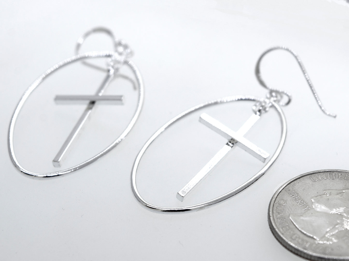 
                  
                    A pair of Super Silver Modern Cross Earrings with an oval wire design casing.
                  
                