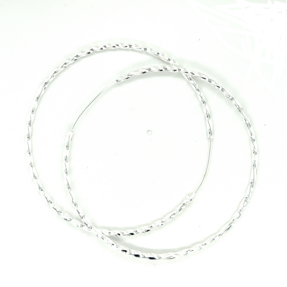 A pair of 70mm Twisted Hoops made of sterling silver by Super Silver on a white surface.