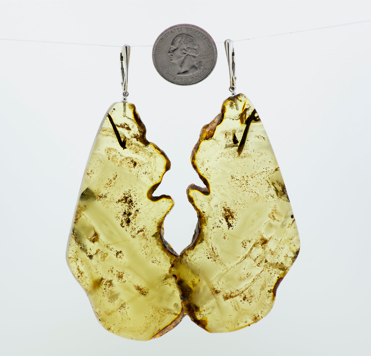 A pair of Designer Raw Cognac Amber Slab Earrings by Super Silver hanging on a wire.