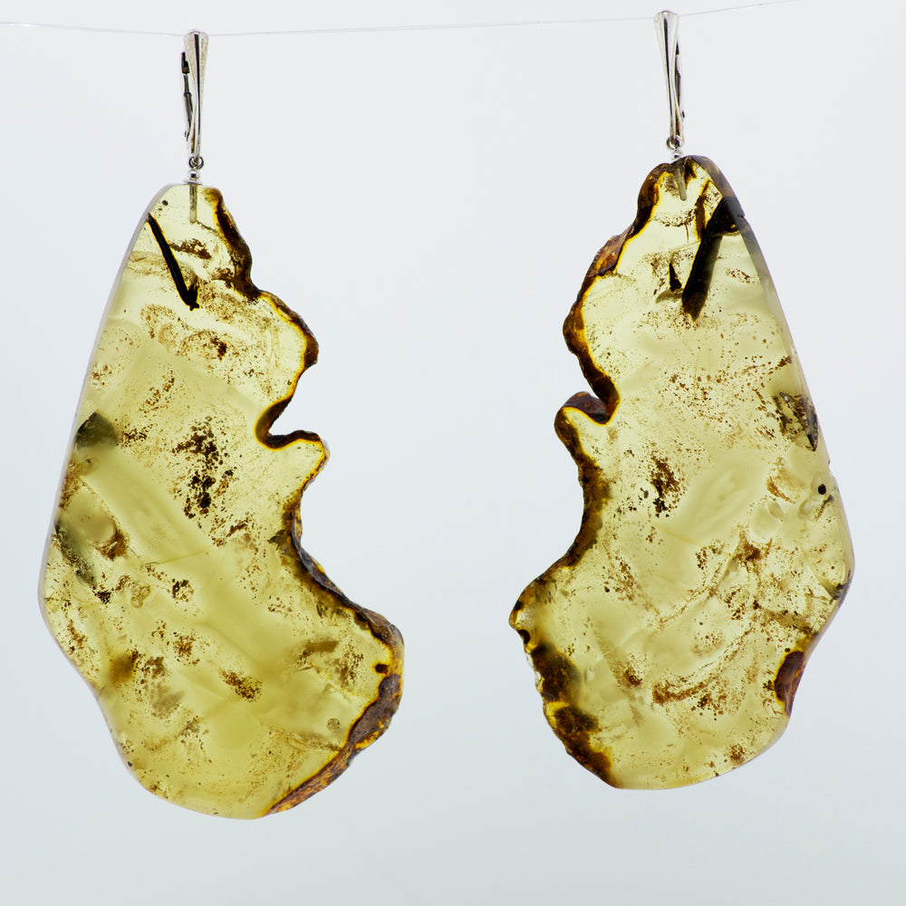 
                  
                    A pair of Designer Raw Cognac Amber Slab Earrings hanging from a wire. (Brand: Super Silver)
                  
                