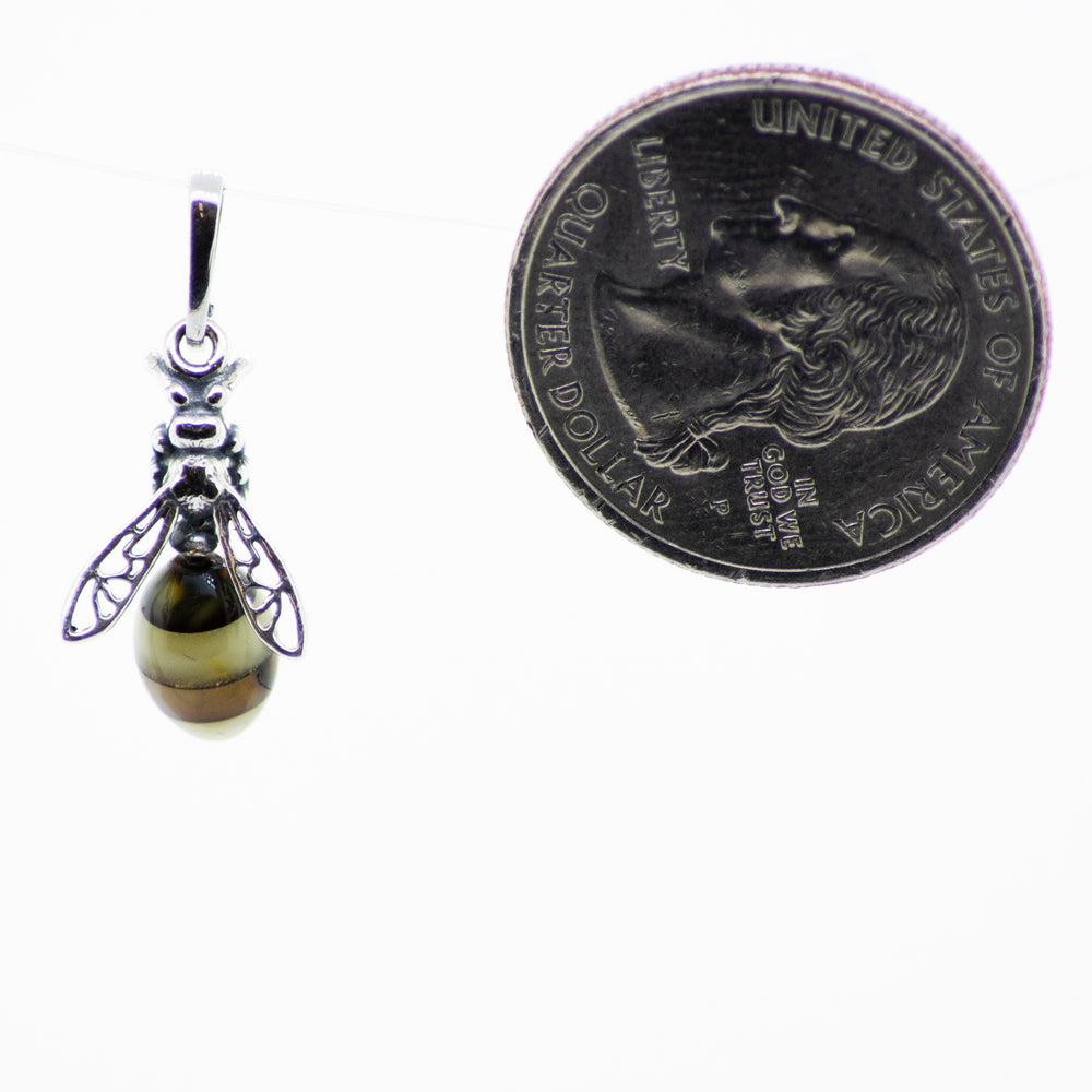 A bee with filigree wings is sitting on top of a dime, showcasing a unique Super Silver Beautiful Amber Yellow Jacket Pendant.