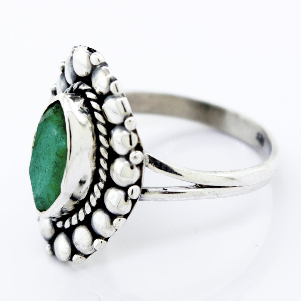 A Super Silver Marquise Shaped Vibrant Emerald Ring with an emerald stone on a white surface.