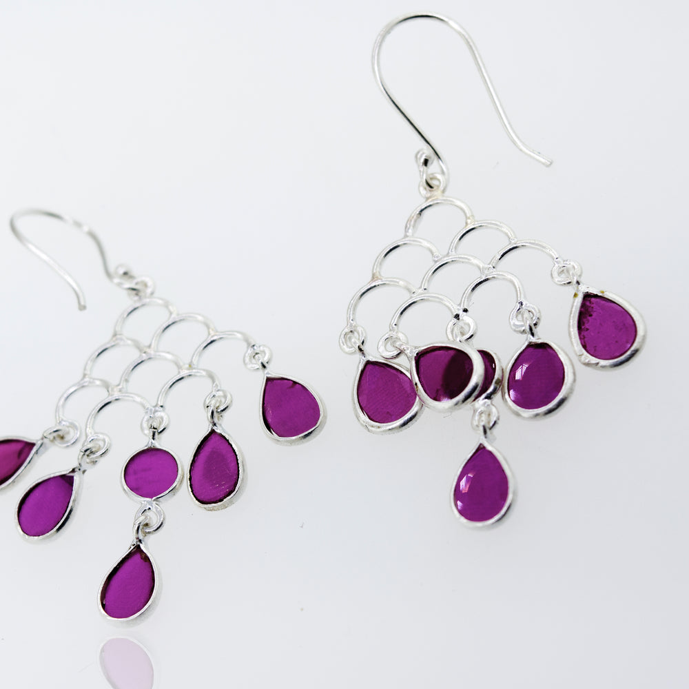 
                  
                    A pair of purple Faceted Ruby Chandelier Earrings by Super Silver on a white surface.
                  
                