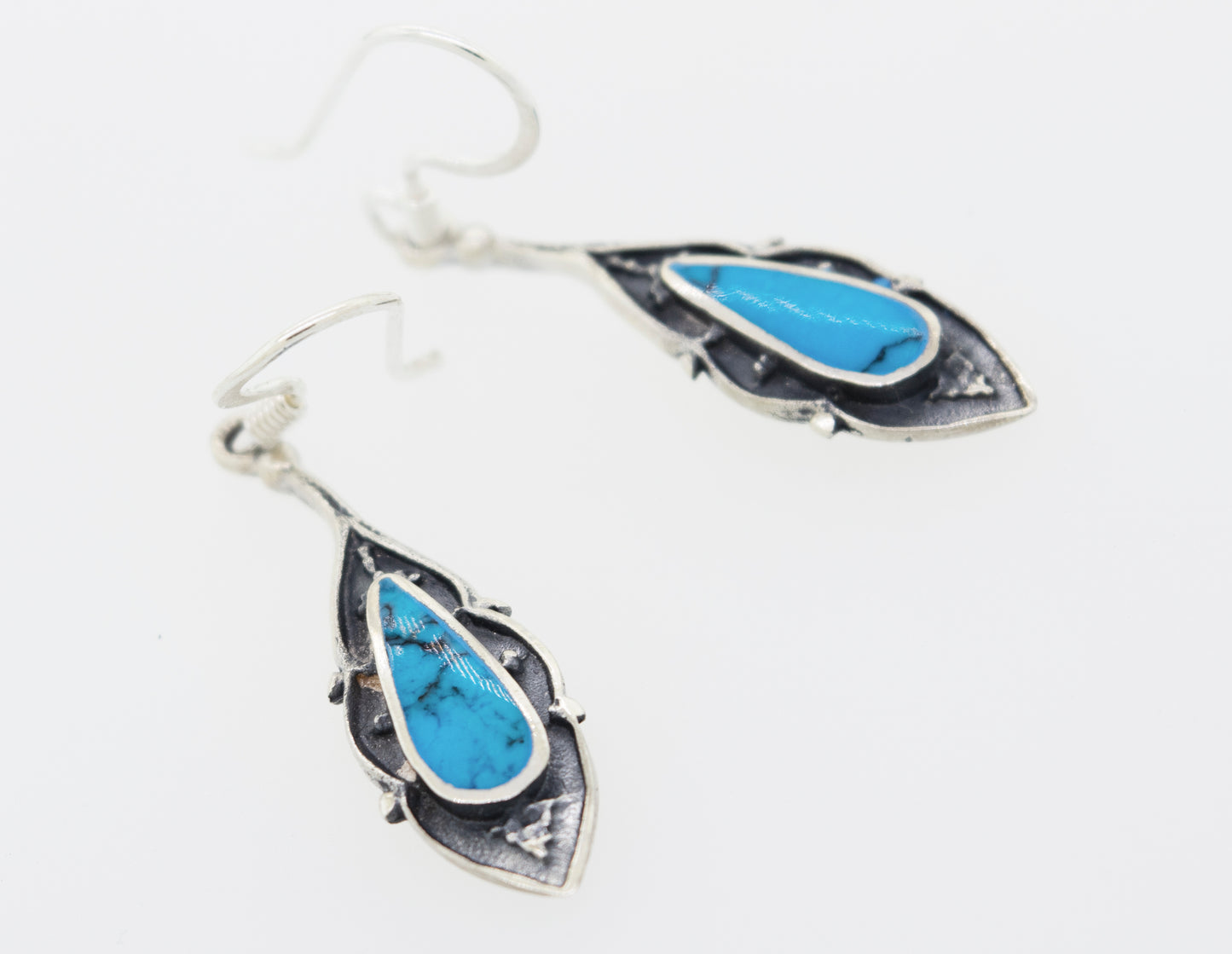 A pair of Super Silver Teardrop Shape Turquoise Earrings adorned with turquoise stones.