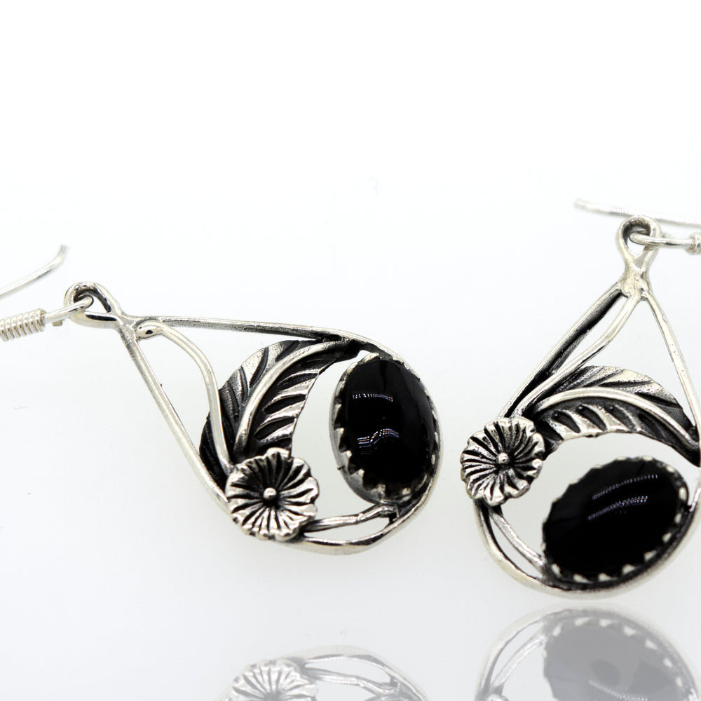 
                  
                    A pair of black Super Silver Onyx Teardrop Earrings With Floral Setting made of 925 Sterling Silver on a white surface.
                  
                