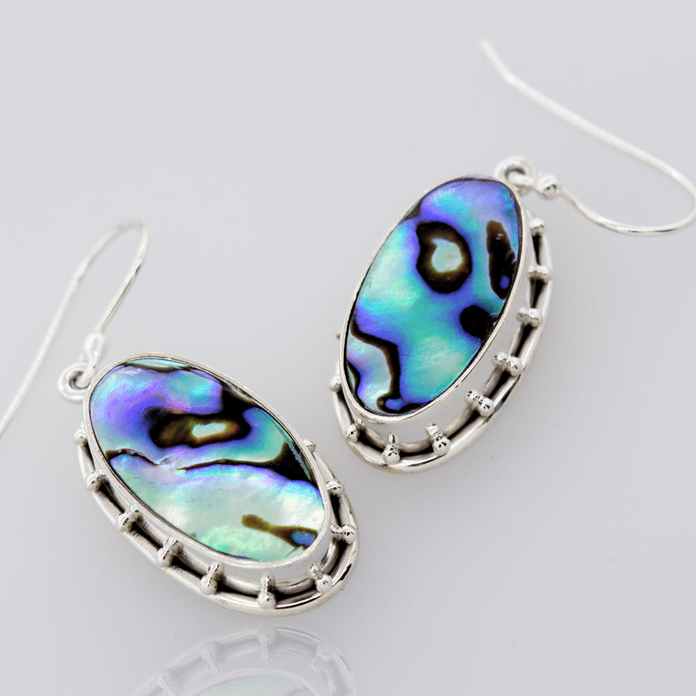 
                  
                    A pair of Super Silver oval abalone earrings on a white surface.
                  
                