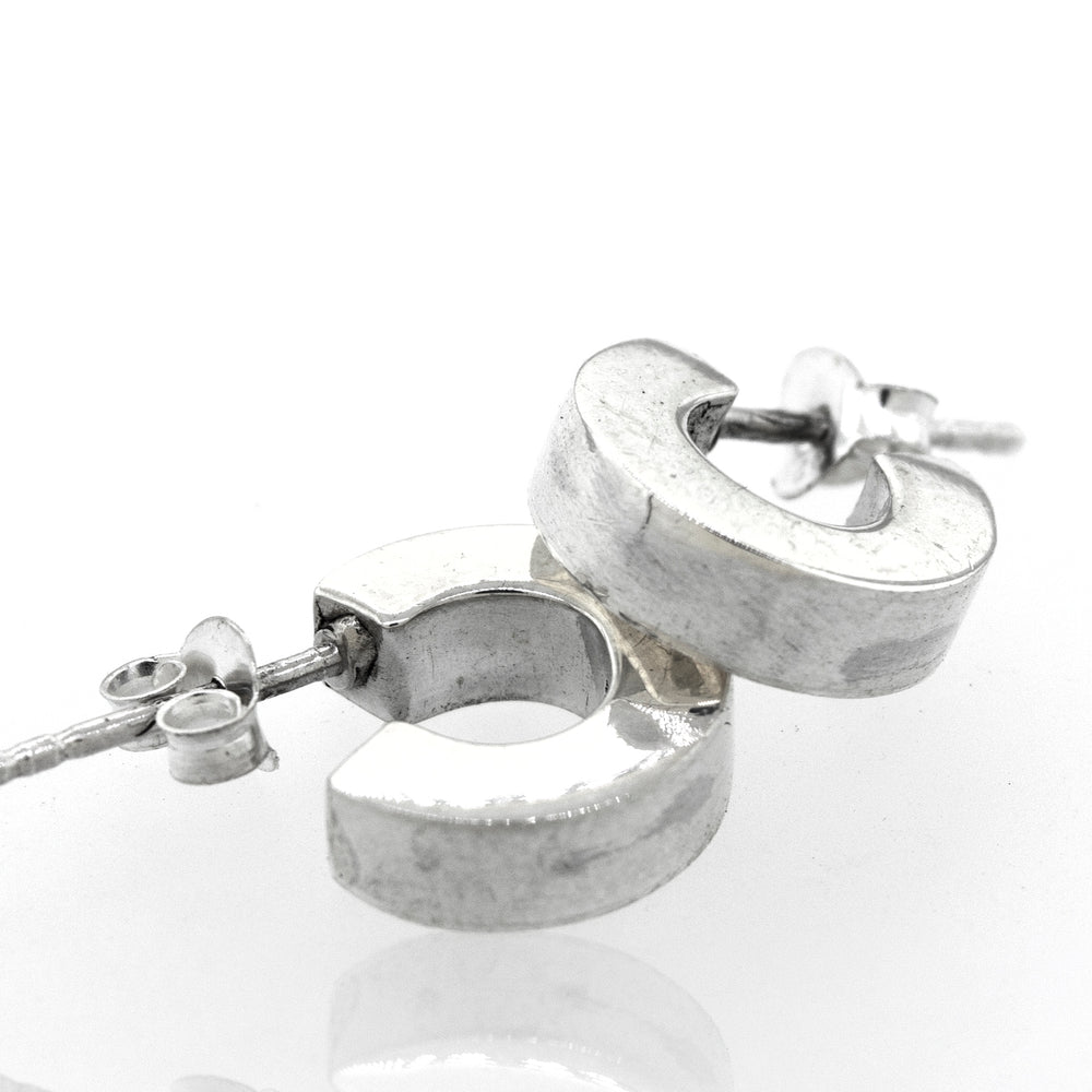 A pair of Super Silver Sterling Silver Half Hoop Stud Earrings on a white surface.
