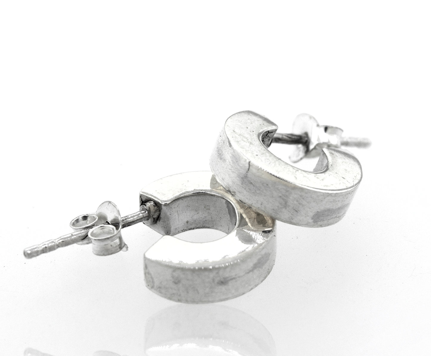 A pair of Super Silver Sterling Silver Half Hoop Stud Earrings on a white surface.
