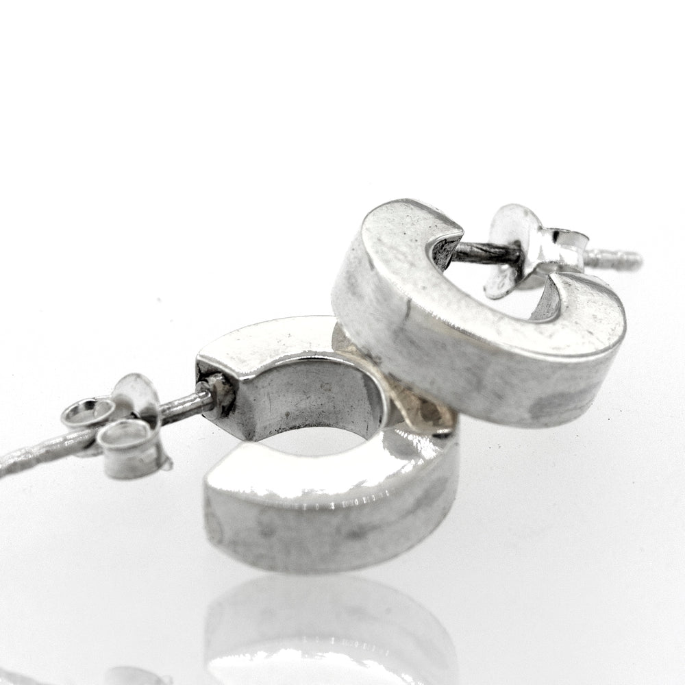 A pair of Super Silver Sterling Silver Half Hoop Stud Earrings with a high polish on a white surface.