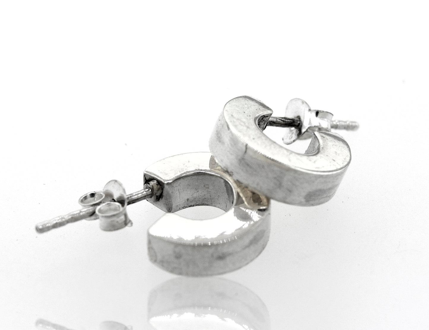 A pair of Super Silver Sterling Silver Half Hoop Stud Earrings with a high polish on a white surface.