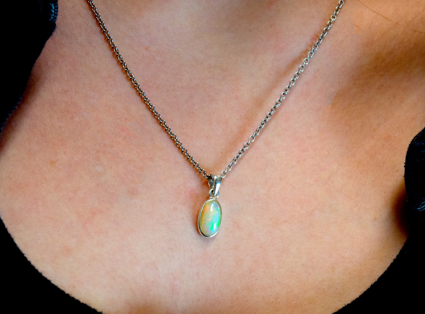 A close up of a woman with a Super Silver Magical Ethiopian Opal Pendant necklace.