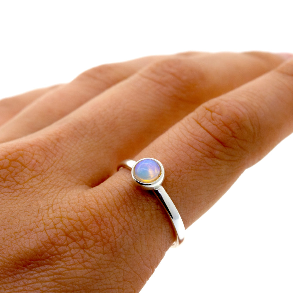 An elegant woman's hand holding a statement Glowing Ethiopian Opal Ring.
