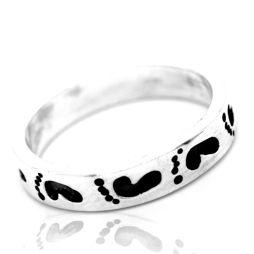 A Super Silver Footprint Band Ring with black footprints, perfect for the beach lover in your life.
