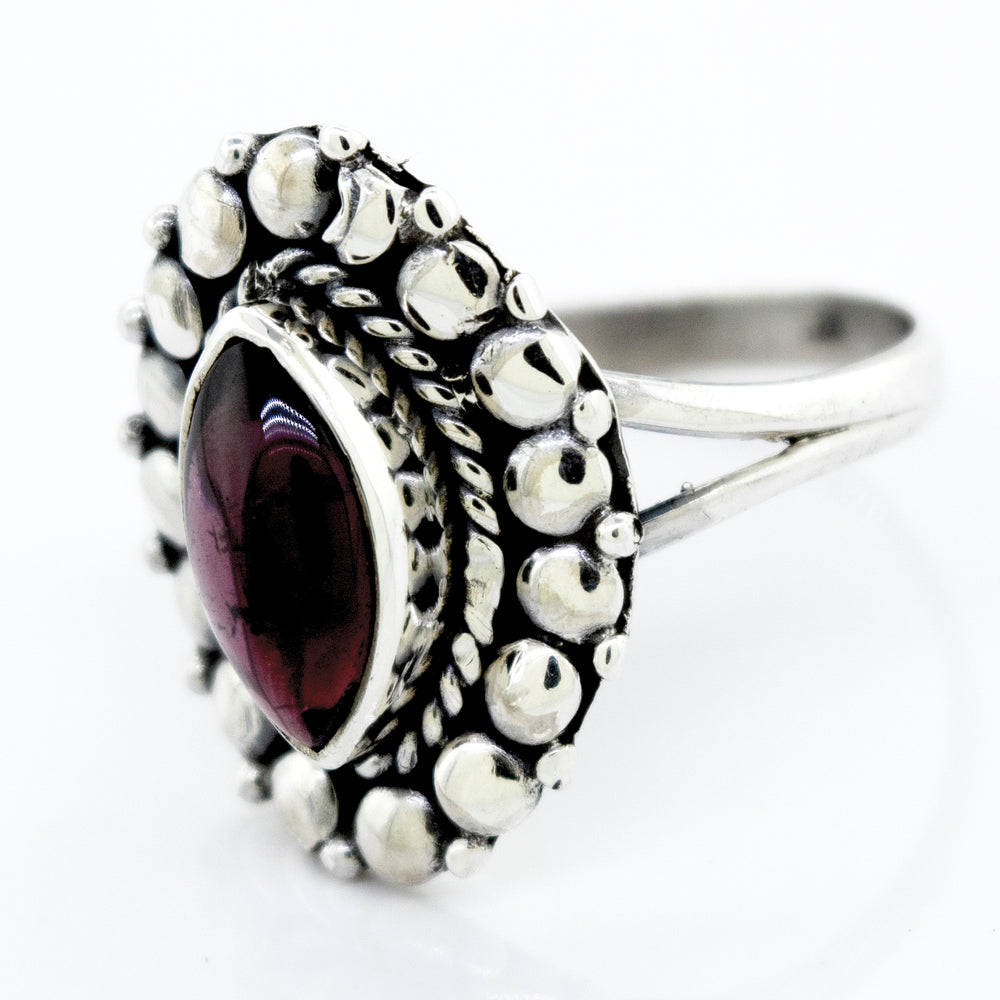 
                  
                    A Marquise Shaped Vibrant Garnet Ring by Super Silver, featuring a beaded design in the silver setting.
                  
                