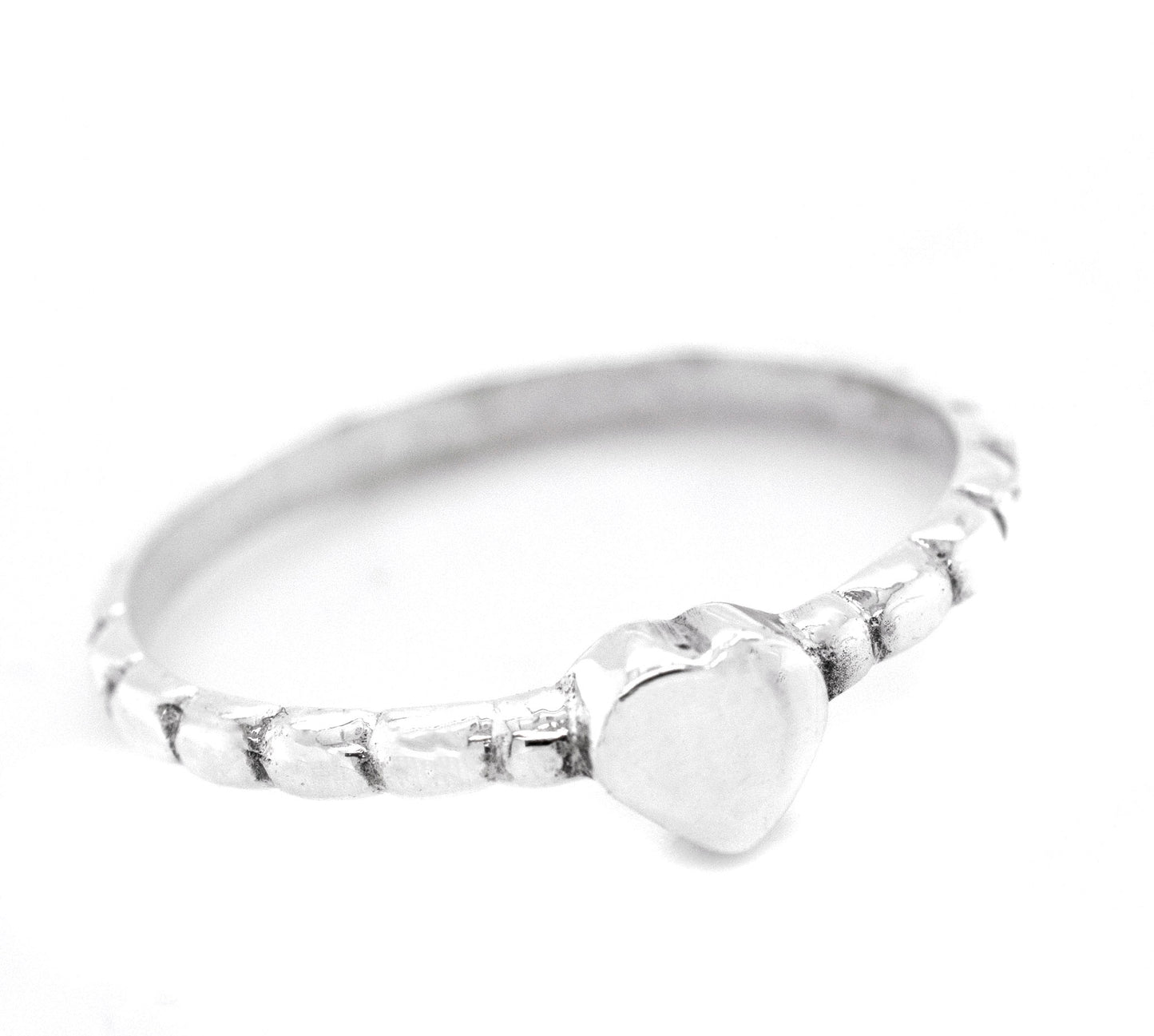 
                  
                    A sterling silver ring with a Petite Patterned Heart Band on a white background.
                  
                