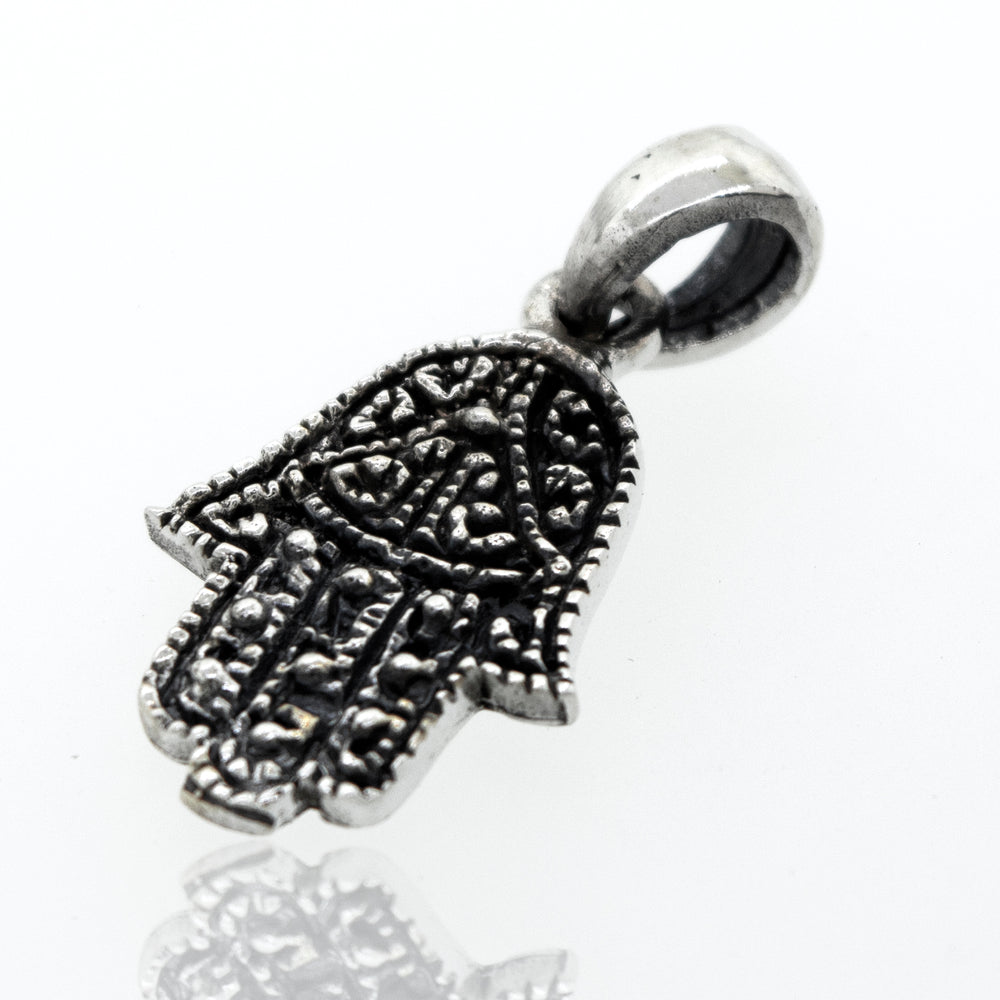 
                  
                    A small Super Silver Hamsa Hand Pendant on an oxidized background.
                  
                