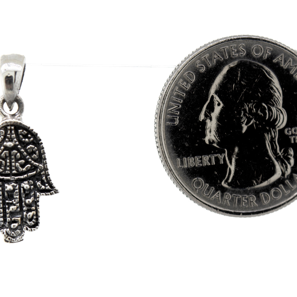 
                  
                    A Super Silver small Hamsa hand pendant made of sterling silver next to a dime.
                  
                