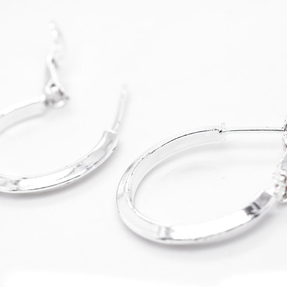 A pair of Super Silver Easy Latch Hoop Earrings on a white surface.