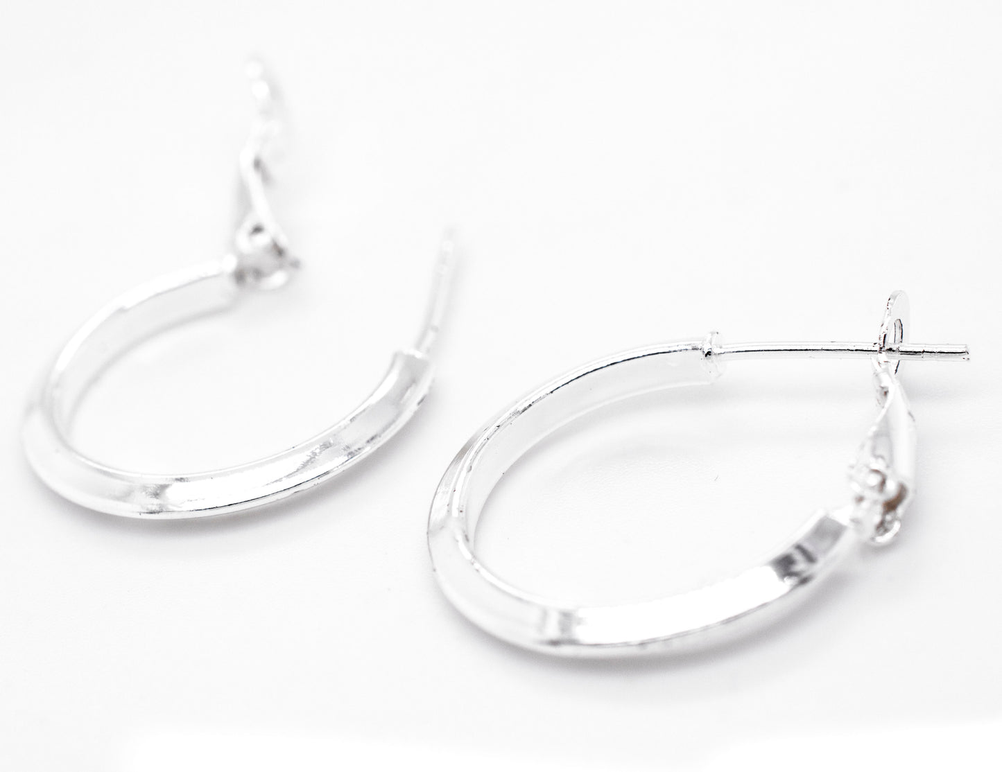 A pair of Super Silver Easy Latch Hoop Earrings on a white surface.