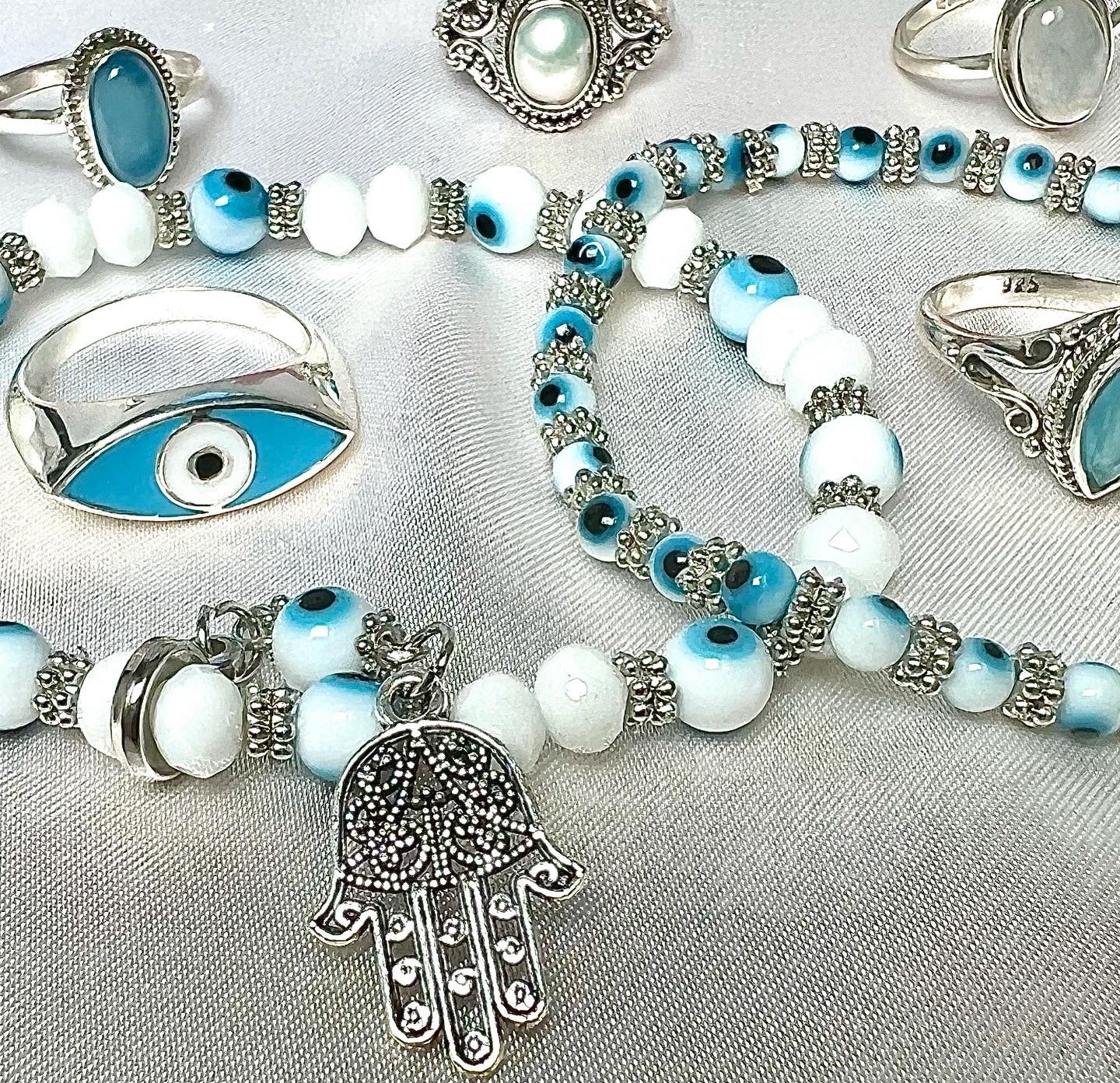 A Super Silver Evil Eye Stretch bracelet with Hamsa Charm adorned with a blue and white evil eye charm and hamsa symbol.