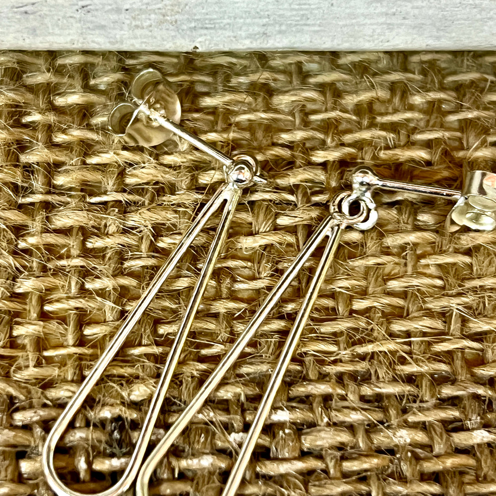 A pair of Everyday Super Silver 925 Sterling Silver elongated open teardrop earrings on a wicker basket.