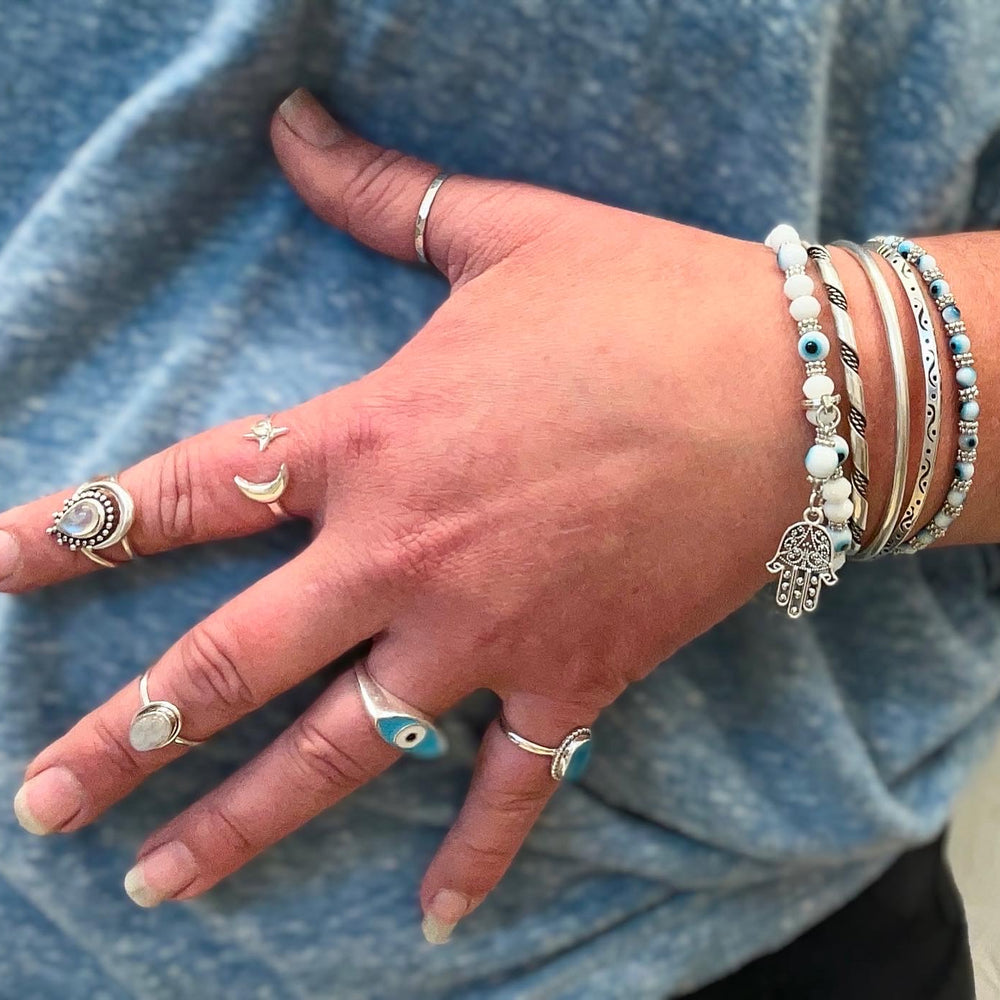 A woman's hand adorned with everyday wear bracelets, including a stunning Super Silver Evil Eye Stretch Bracelet.