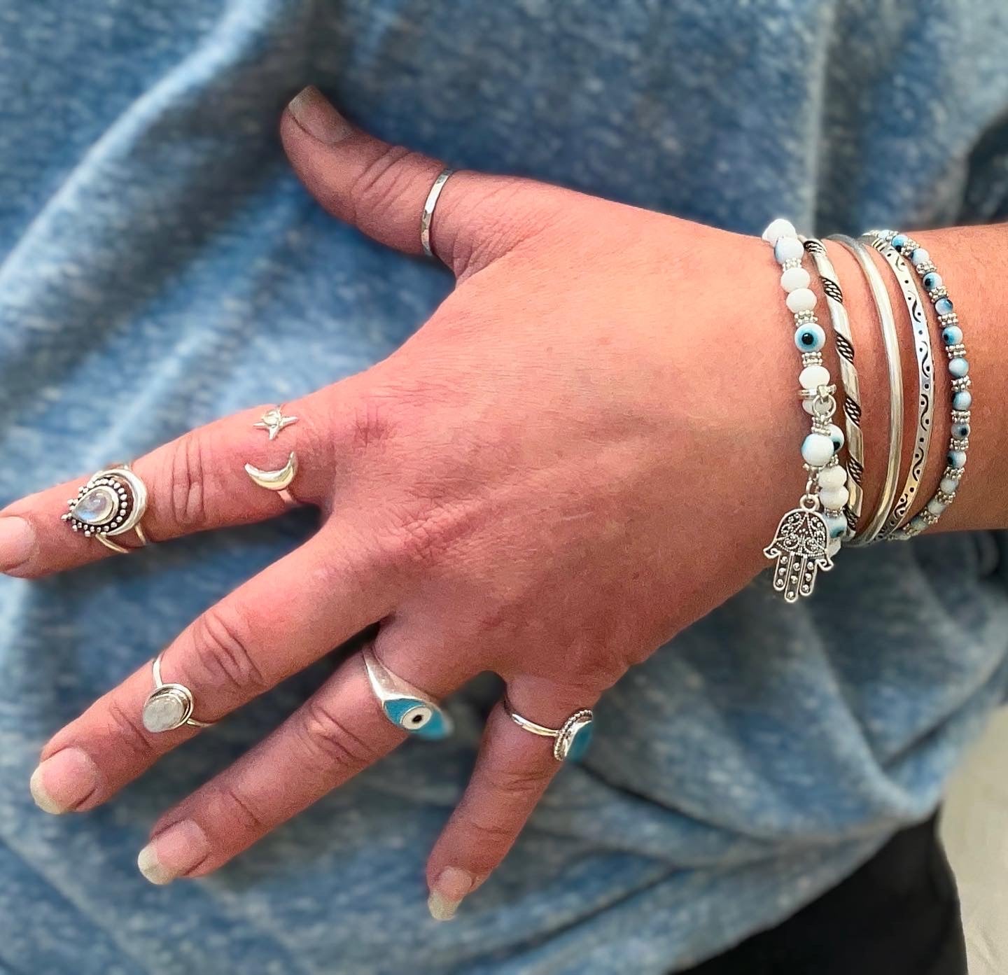 A woman's hand adorned with everyday wear bracelets, including a stunning Super Silver Evil Eye Stretch Bracelet.