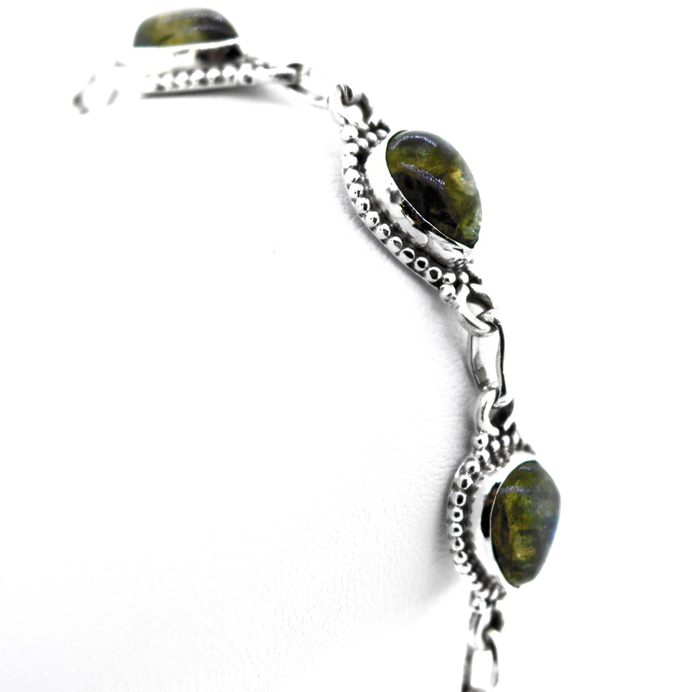 
                  
                    A stunning .925 silver Teardrop Shape Stone Bracelet With Ball Border featuring greenish-black Labradorite oval stones set in intricate metalwork with alternating links.
                  
                