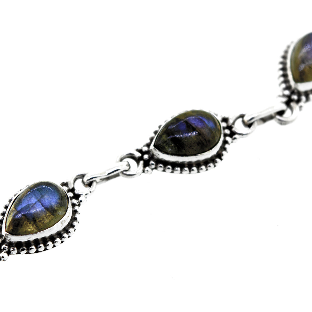 
                  
                    A Teardrop Shape Stone Bracelet With Ball Border crafted from .925 silver, featuring five teardrop-shaped gemstones with a captivating blue iridescent sheen.
                  
                