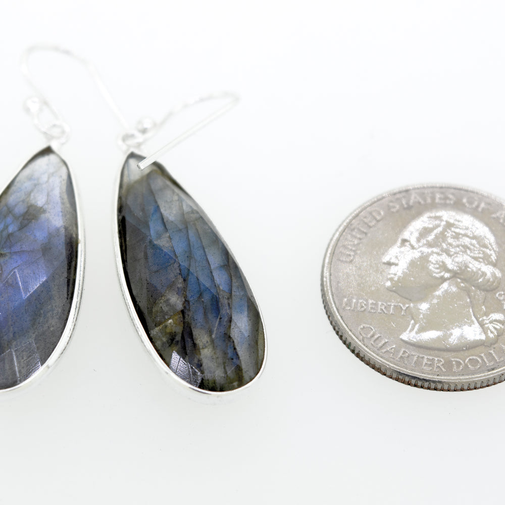 
                  
                    Super Silver's Elegant Facet Cut Teardrop Shape Labradorite Earrings sparkling beside a quarter.
                  
                