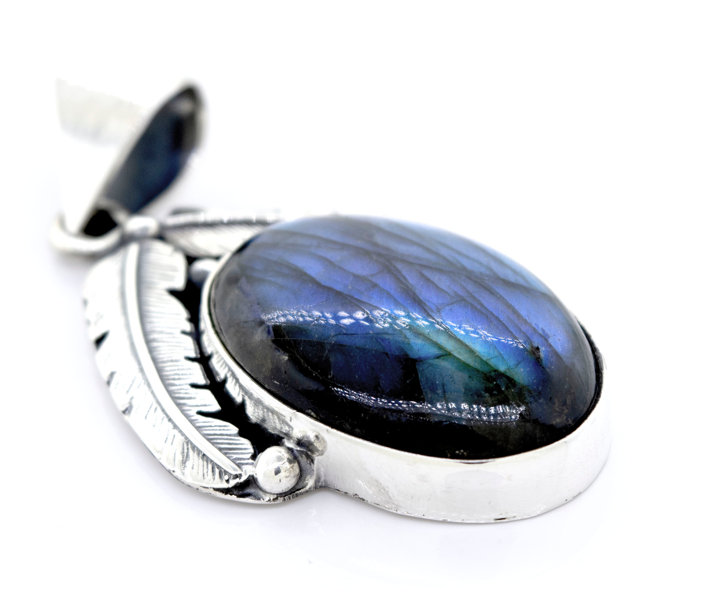 A close-up of the Beautiful Southwest Stone Pendant, featuring a polished oval labradorite stone with a blue and green sheen, set with intricate silver feather detailing.