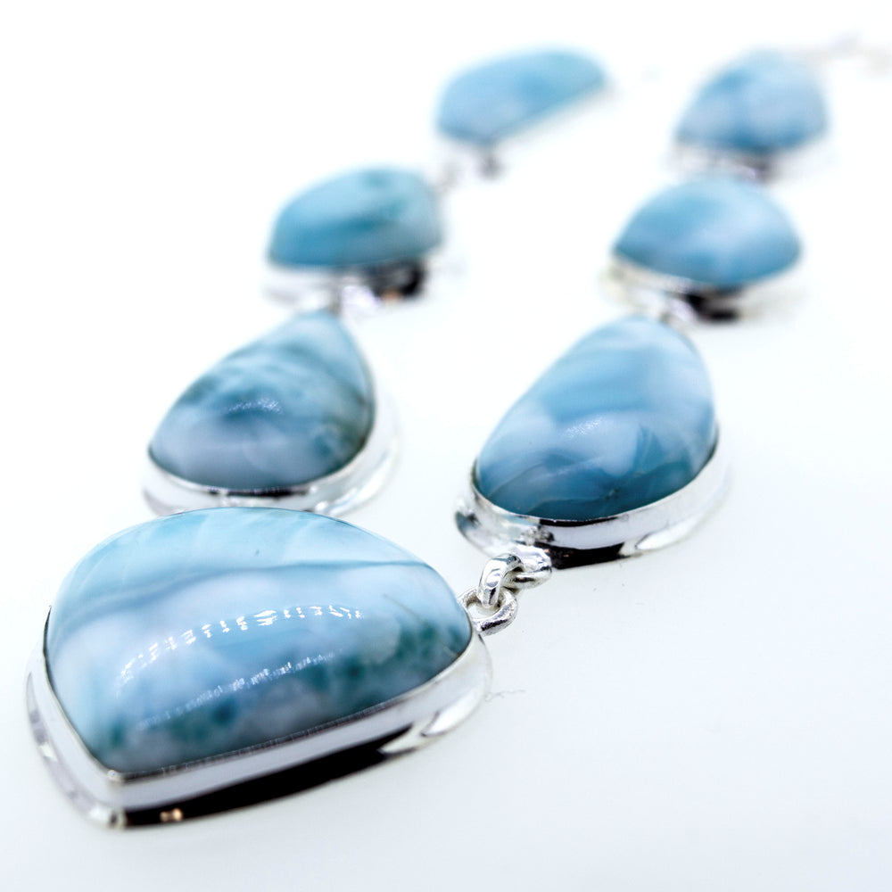 
                  
                    A Super Silver Larimar Necklace adorned with raw natural larimar stones on a white surface.
                  
                