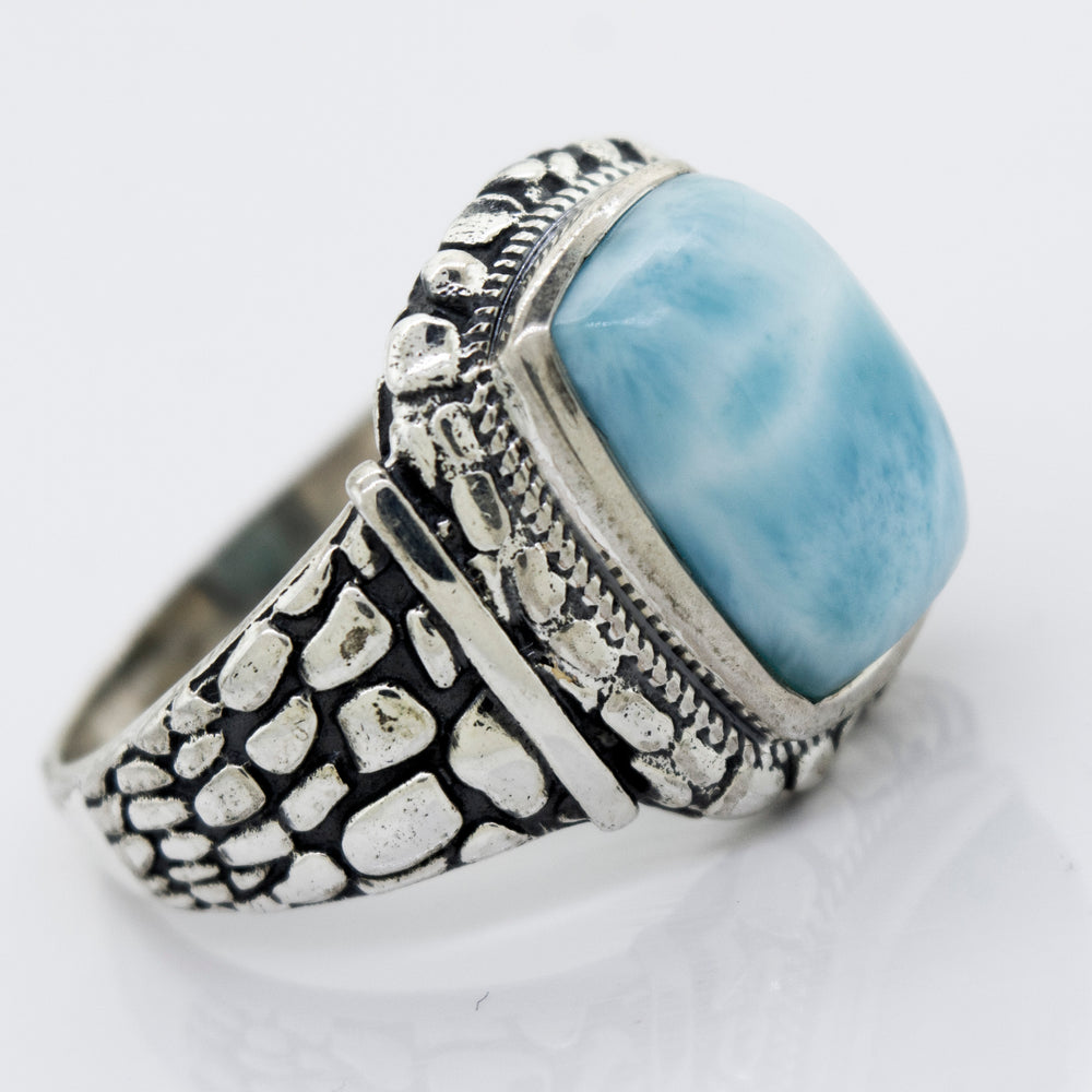 A Larimar Signet Ring With Dragon Scale Pattern with a blue stone.