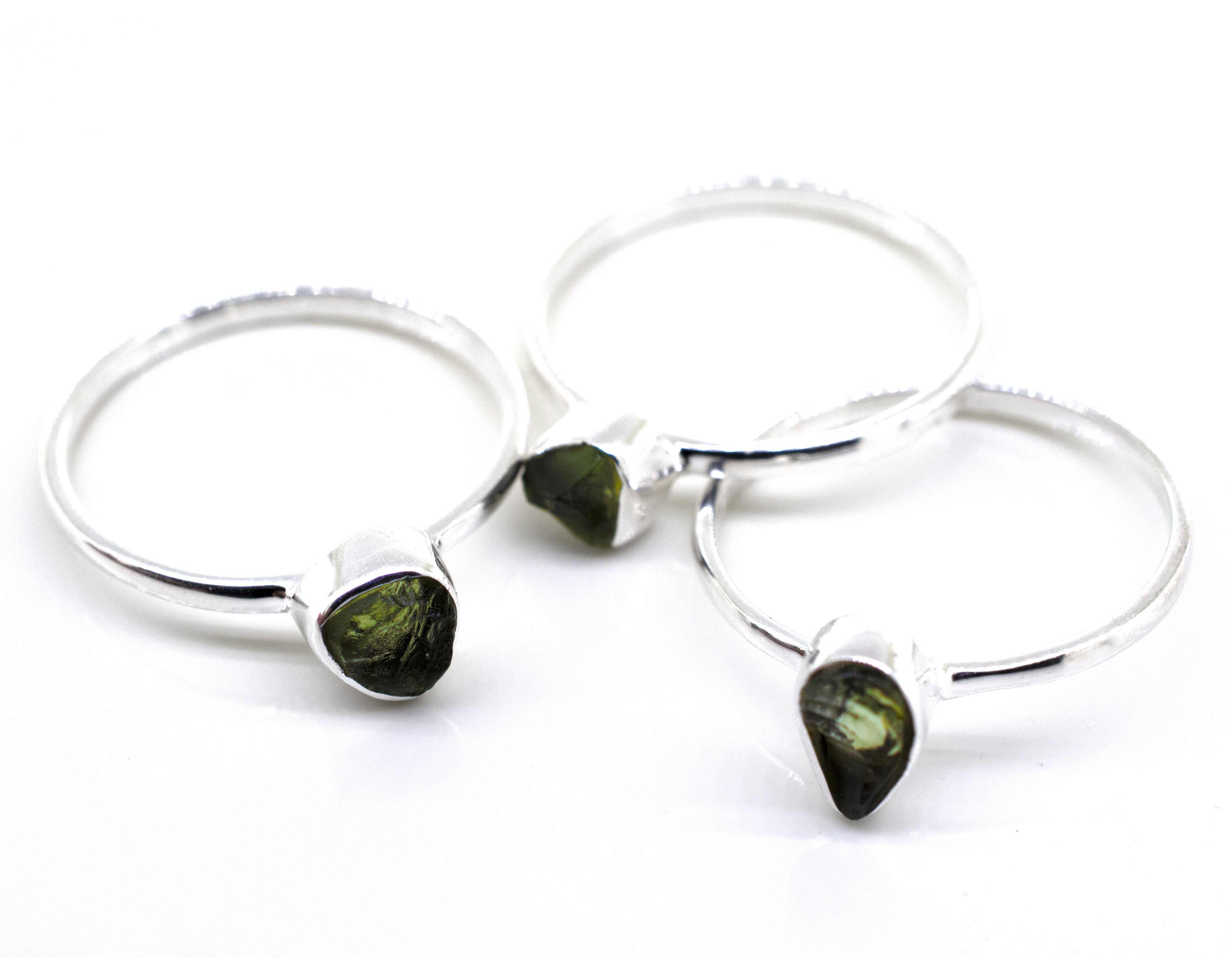 Three Super Silver rings with green tourmaline stones on a white surface, featuring a sterling silver setting.