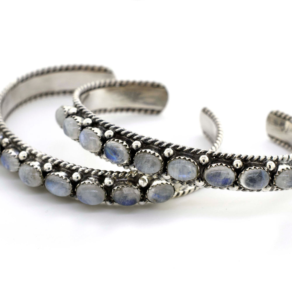 A pair of Super Silver Oval Moonstone Cuff Bracelets, adorned with captivating blue stones, taking wearers on a celestial journey.