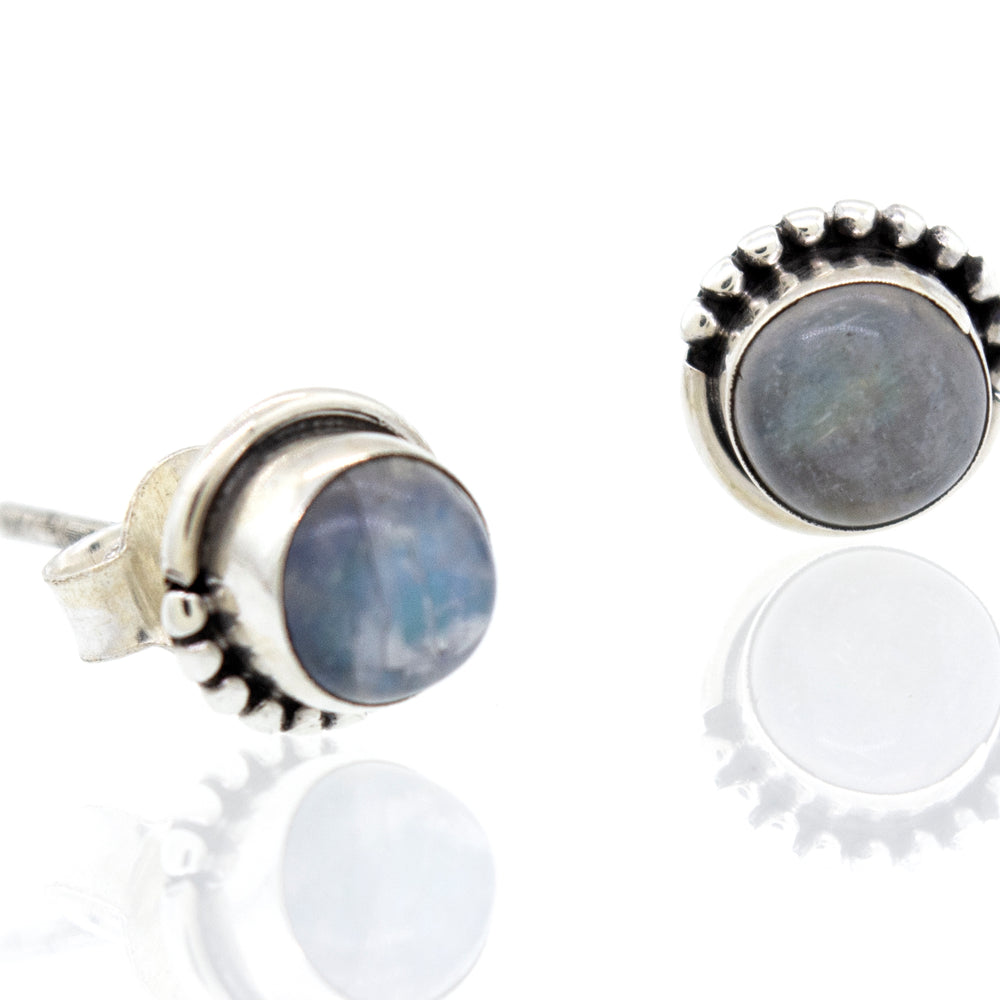 
                  
                    These Small Moonstone Studs with Ball Border earrings, made of .925 sterling silver, feature a stunning 7mm blue stone. Created by Super Silver.
                  
                