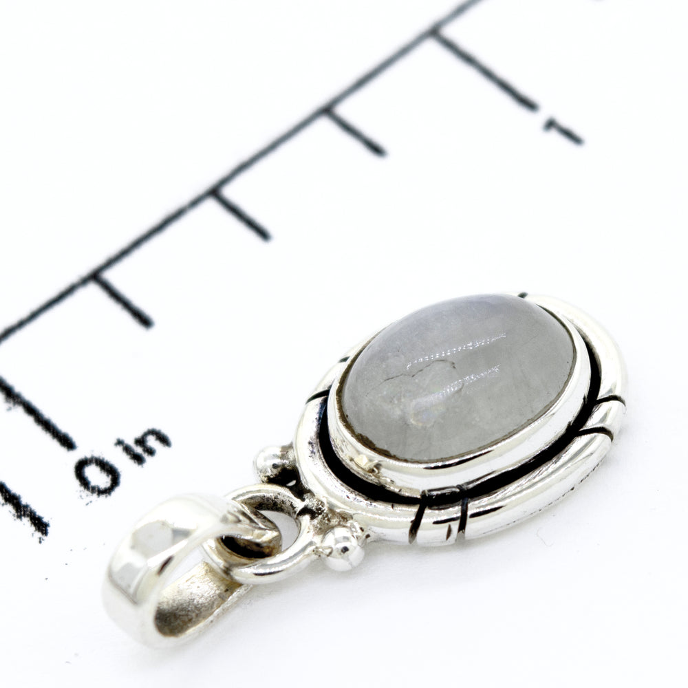 A Simple And Elegant Oval Moonstone Pendant with a moonstone on top of a ruler, perfect for your everyday outfit, by Super Silver.