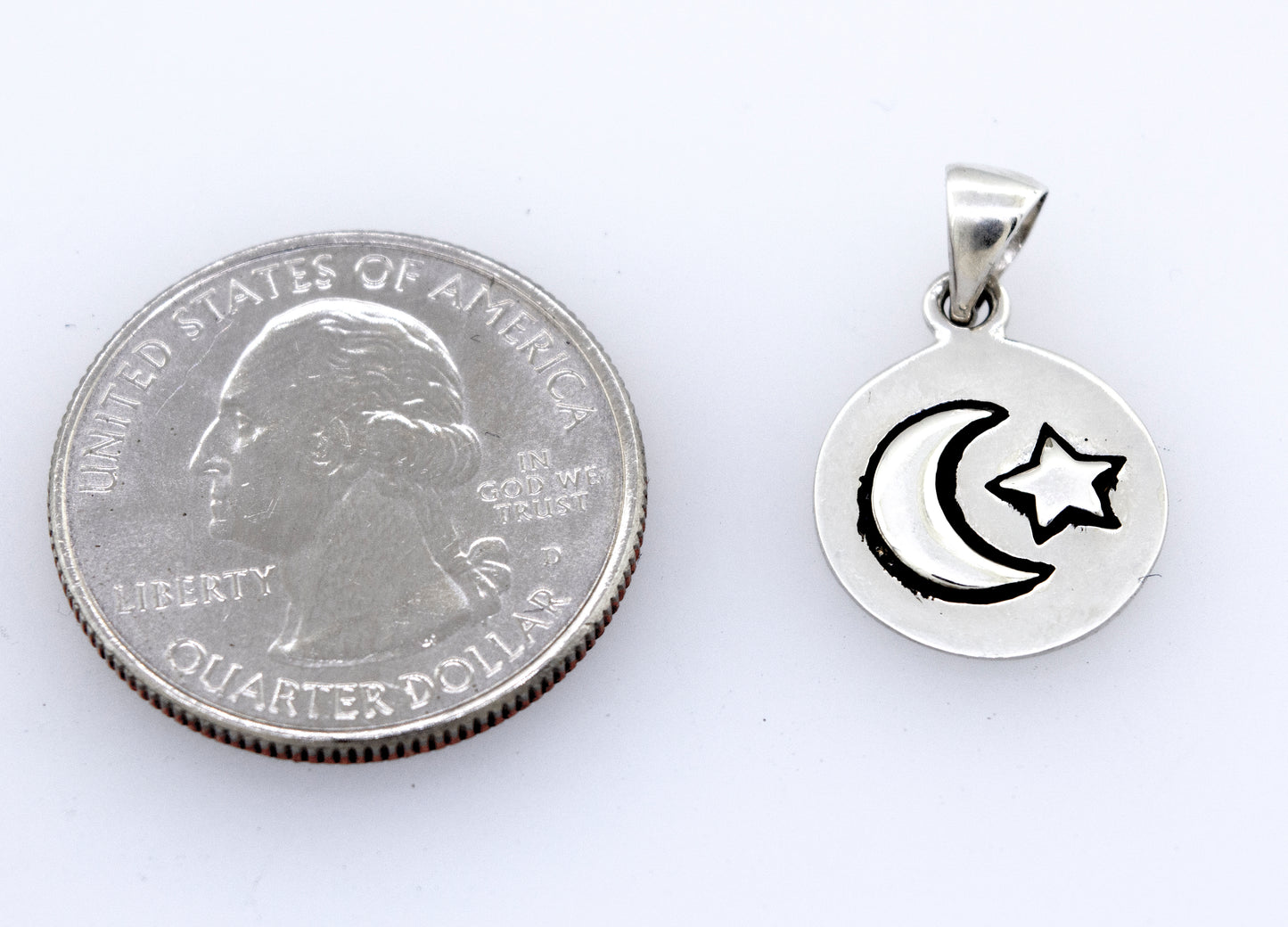 
                  
                    An interstellar Moon And Star Pendant featuring a silver crescent and star, complemented by an oxidized finish, placed next to a dime, made by Super Silver.
                  
                