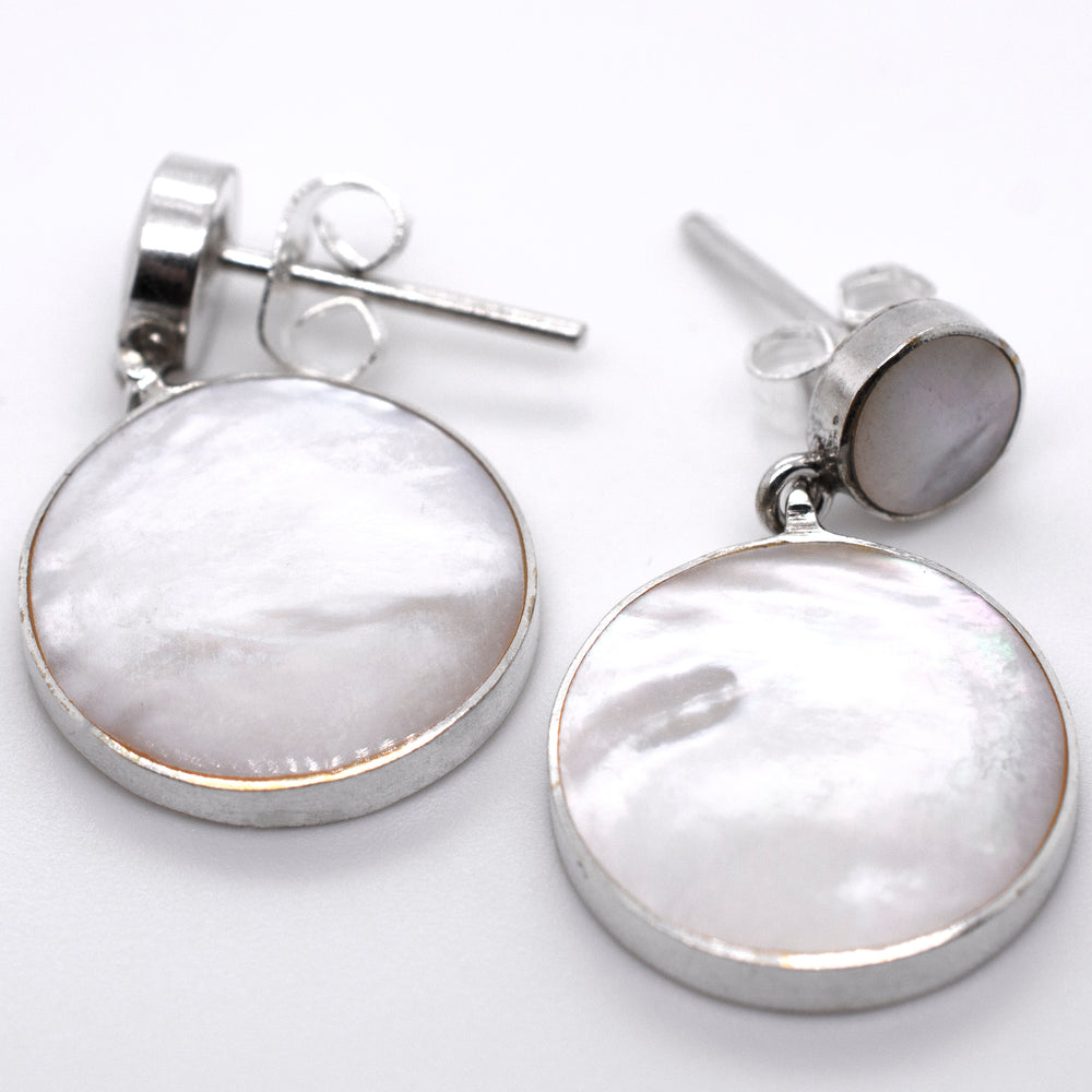A pair of Super Silver Round Mother Of Pearl Earrings With Post on a white surface.