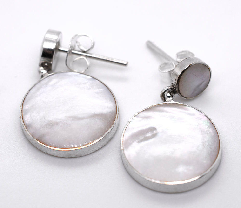 A pair of Super Silver Round Mother Of Pearl Earrings With Post on a white surface.