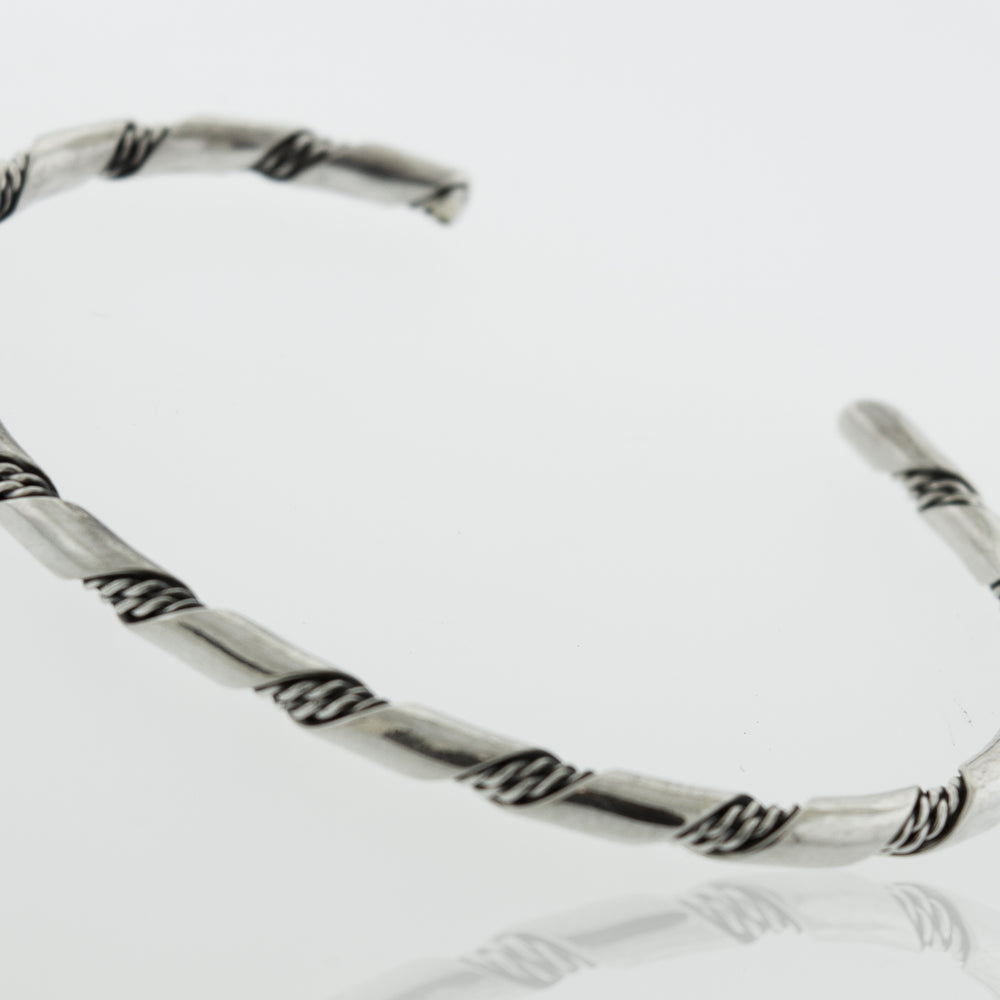 
                  
                    A Native American Handmade Thin Silver Twist Cuff from Super Silver, with a braided design, perfect for stacking or adding a stylish touch to any outing.
                  
                