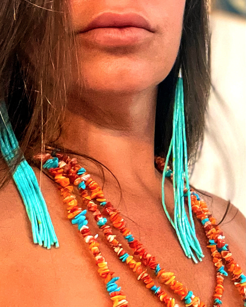 
                  
                    A woman wearing a Handmade Spiny Oyster Shell and Turquoise Necklace with tassels by Super Silver.
                  
                