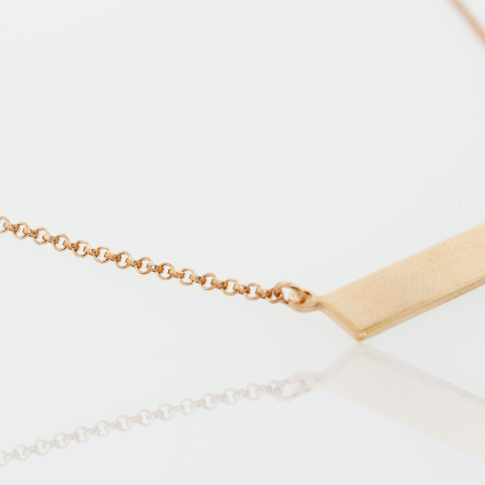 A Super Silver Dainty Nameplate Necklace on a white surface with an adjustable chain.