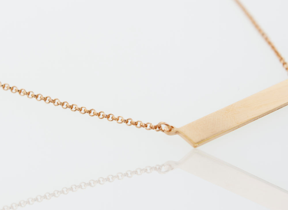 A Super Silver Dainty Nameplate Necklace on a white surface with an adjustable chain.