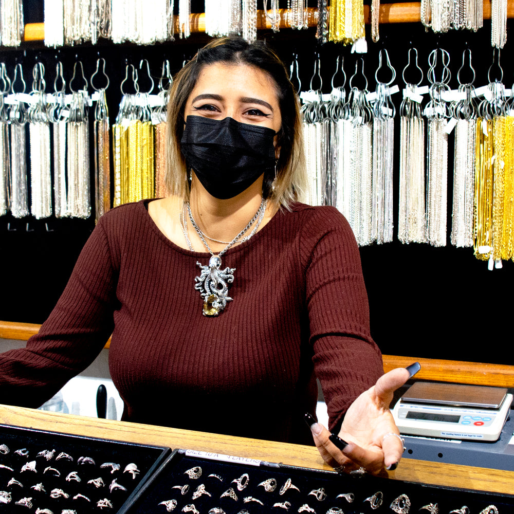 
                  
                    A woman wearing a mask admires a Designer Handmade Octopus Pendant With Vibrant Citrine Crystal from Super Silver in a jewelry store.
                  
                