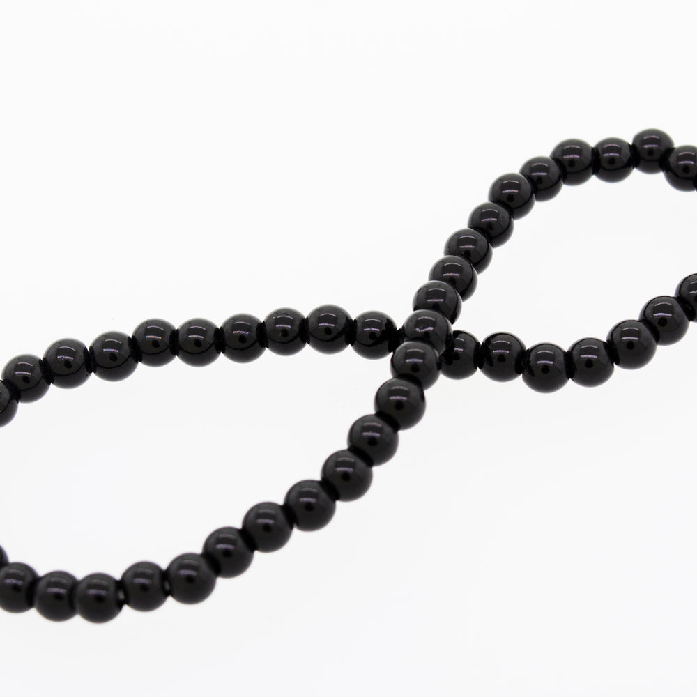 
                  
                    A black onyx bead on a white background, part of the Small Stone Beads Bracelet by Super Silver.
                  
                