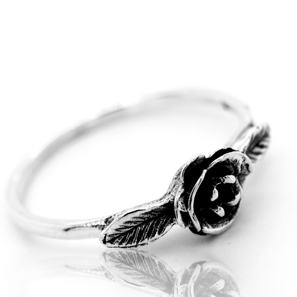 A floral silver ring with the Fashionable Rose Ring on it.
